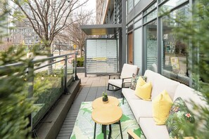 An outdoor seating area with a sofa, chairs, and a small table, overlooking a city street. - Private Home, 3 BR, Rogers Centre & Free Parking (Toronto)
