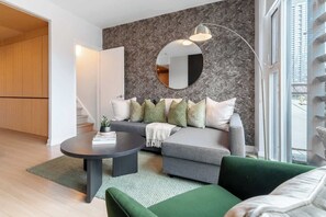 A modern living room with a grey sofa, green armchair, and a round mirror on the wall. - Private Home, 3 BR, Rogers Centre & Free Parking (Toronto)