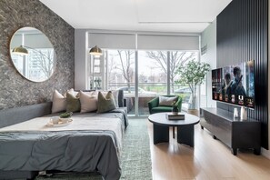 A modern living room with a bed, a sofa, a coffee table, and a television. - Private Home, 3 BR, Rogers Centre & Free Parking (Toronto)