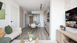 A modern living room with a sofa, coffee table, and a TV displaying 'Stranger Things'. - Chic 2BR Urban High-Rise Scenic City Views (Toronto)