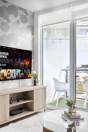 A modern living room with a large flat-screen TV mounted on the wall displaying a movie.