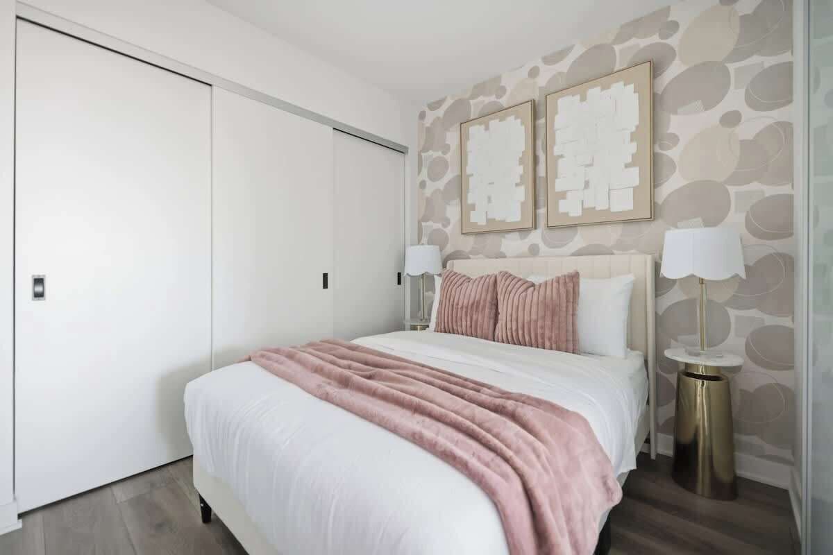 A bedroom with a bed, bedside tables, a wardrobe, and wall art.