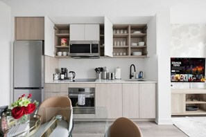 A modern kitchen with a built-in refrigerator, microwave, and oven. There is a dining area with a table and chairs.