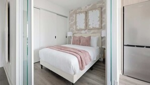 A bedroom with a bed, a wardrobe, and a wall-mounted artwork.