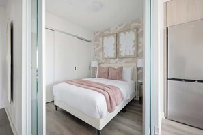 A bedroom with a bed, a wardrobe, and a wall-mounted artwork.