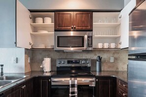 A modern kitchen with a stainless steel microwave, oven, and refrigerator. - Chic Fort York Haven Lake Views & City Pulse (Toronto)