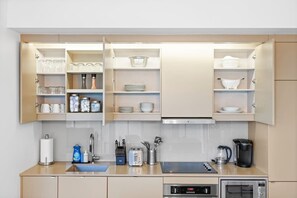 Eine moderne Küche mit eingebauten Schränken, einer Spüle, einem Toaster, einer Kaffeemaschine und einer Mikrowelle.