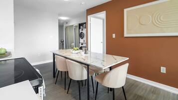 A modern kitchen with a black countertop, a dining table with four chairs, and a wall-mounted oven.