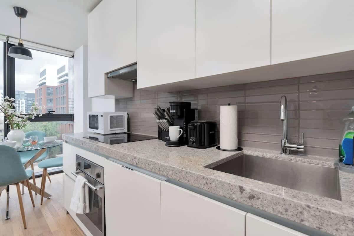 A modern kitchen with a large window, a built-in microwave, a coffee maker, and a stainless steel sink.