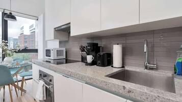 A modern kitchen with a large window, a built-in microwave, a coffee maker, and a stainless steel sink.