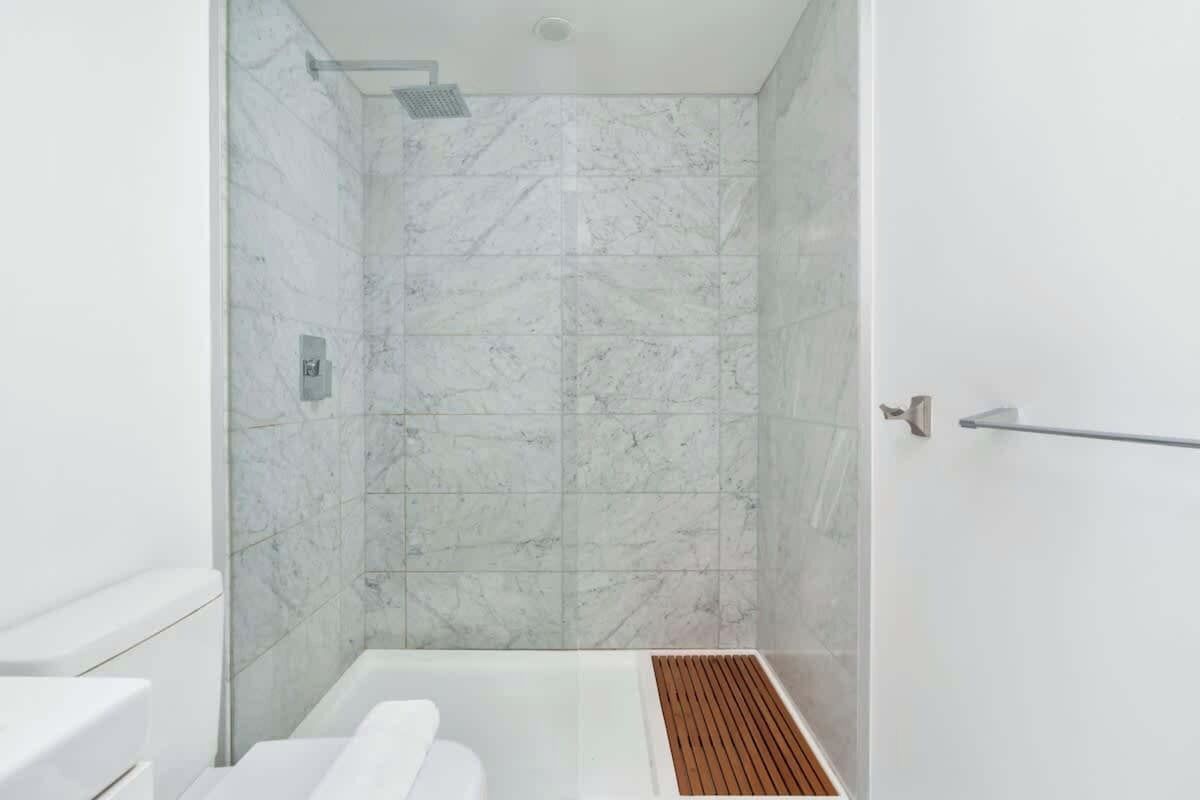Un bagno moderno con cabina doccia in vetro, un water bianco e un pavimento in legno.
