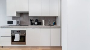 A modern kitchen with white cabinets, a microwave, a coffee maker, and a sink. - Chic City Oasis with Cafes & Bars at your Doorstep! (Toronto)