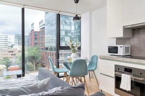 A modern apartment with a large window, a dining area, a kitchenette, and a bed. - Chic City Oasis with Cafes & Bars at your Doorstep! (Toronto)