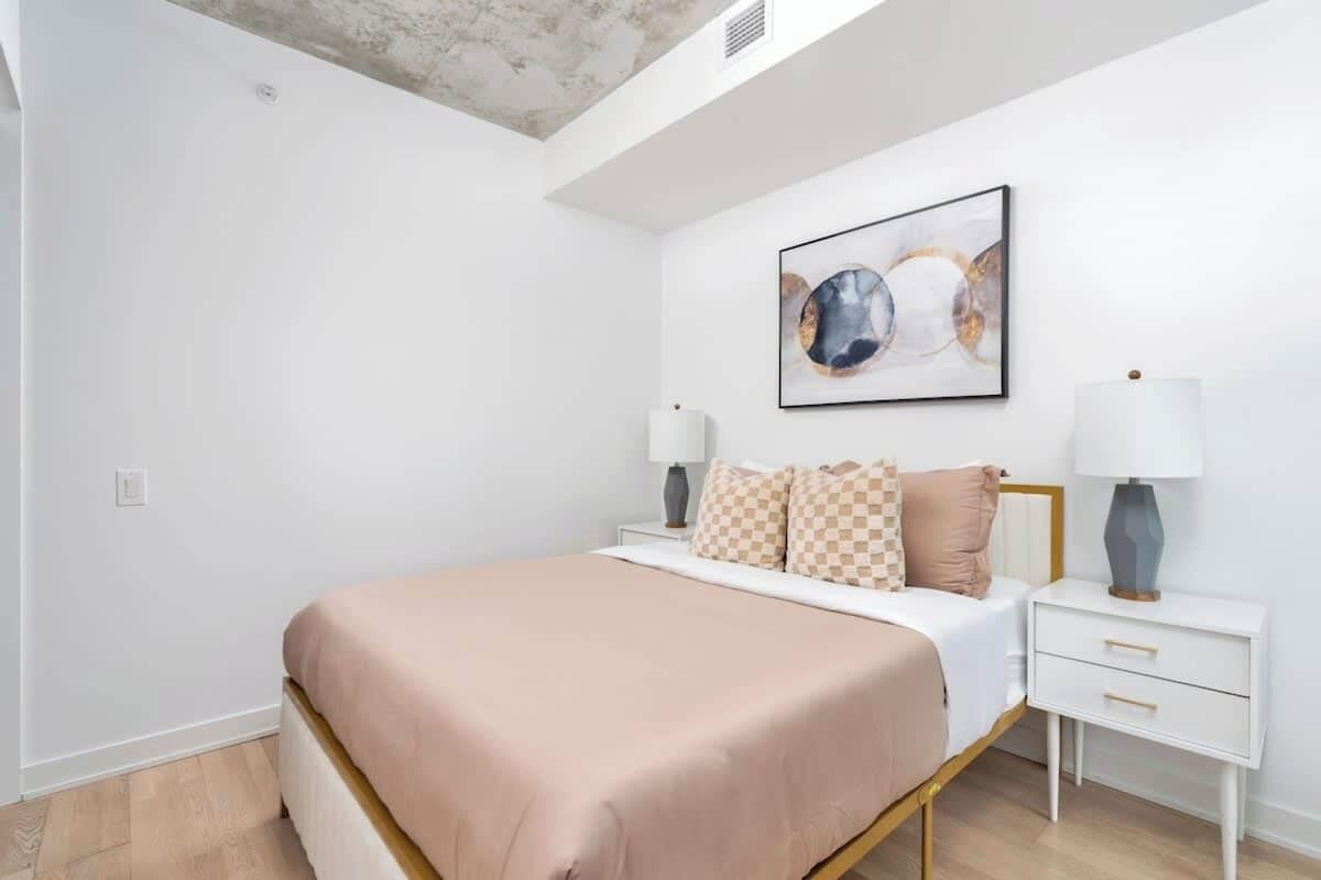 A bedroom with a bed, bedside tables, and a ceiling light fixture.