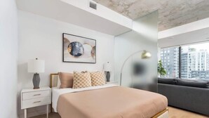 A modern bedroom with a bed, bedside table, lamp, and a city view. - Chic City Oasis with Cafes & Bars at your Doorstep! (Toronto)