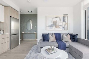 A modern living room with a grey sofa, a white coffee table, and a large abstract painting on the wall.