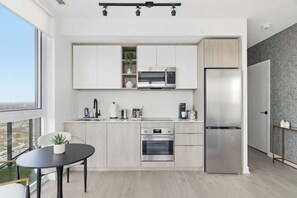 A modern kitchen with white cabinets, stainless steel appliances, and a dining area with a black table and chairs.