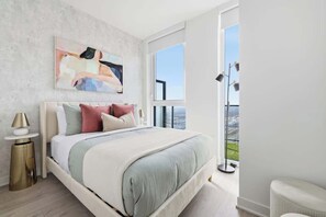 A modern bedroom with a large bed, a view of the city, and a balcony. - Modern 2BR Retreat w Private Terrace | Parking (Toronto)