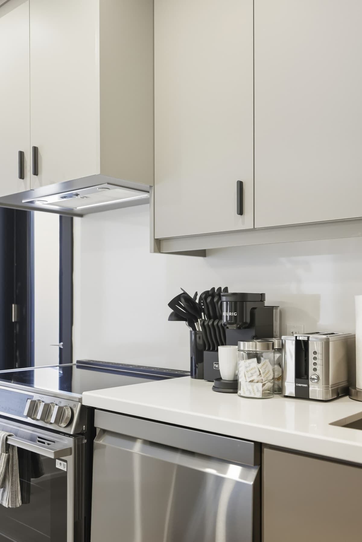 Une cuisine moderne équipée d’appareils électroménagers en acier inoxydable, notamment un lave-vaisselle, un four et une machine à café.