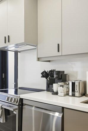 A modern kitchen with stainless steel appliances, including a dishwasher, oven, and coffee maker.