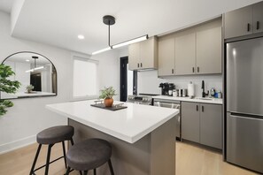A modern kitchen with a central island, stainless steel appliances, and a minimalist design. - Elegant 2BR Retreat, Sleek Design & Comfort | Parking Available (Toronto)