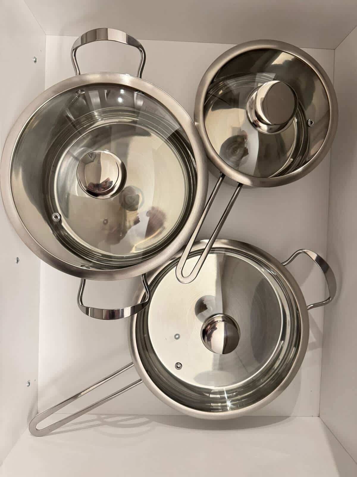 Three stainless steel pots with lids, arranged in a box.