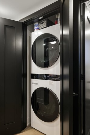Ein kompakter, moderner Waschraum mit zwei wandmontierten Waschmaschinen und einer kleinen Ablage mit einer Waschmittelflasche.