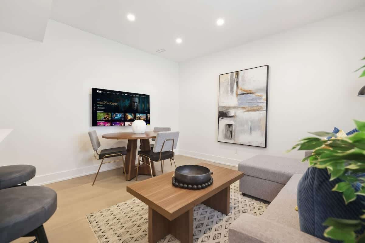 Una sala moderna con una televisión de pantalla plana, una mesa de comedor y un sofá.