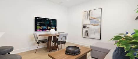 Una sala moderna con una televisión de pantalla plana, una mesa de comedor y un sofá.
