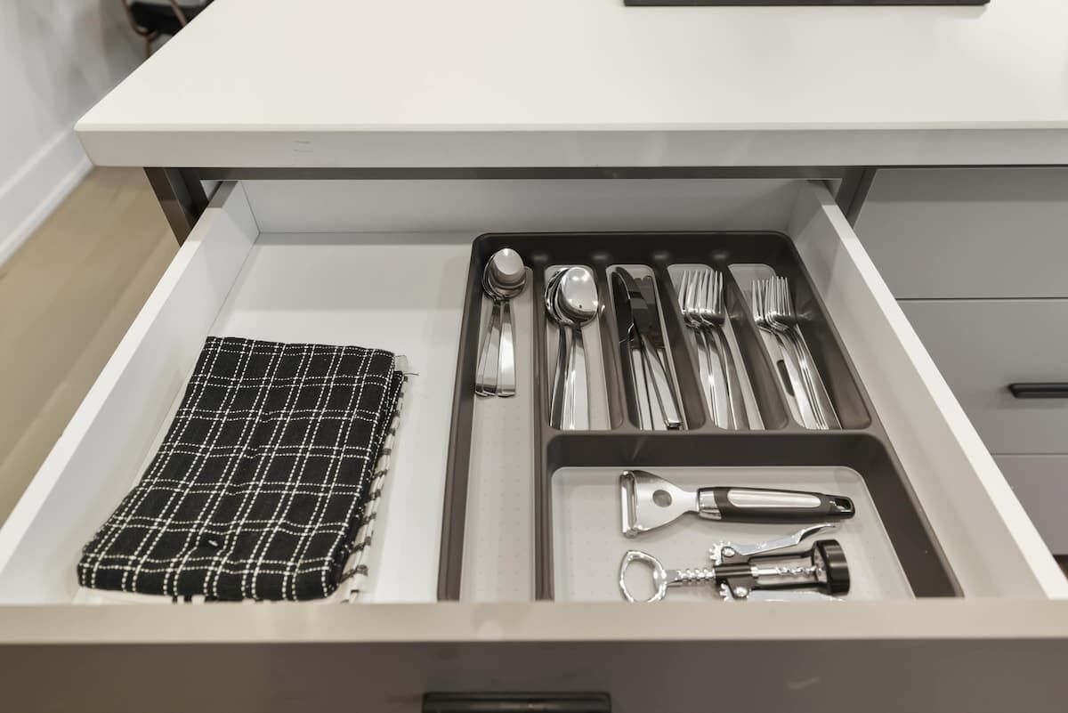 A drawer with neatly organized utensils, a cloth, and a keychain.