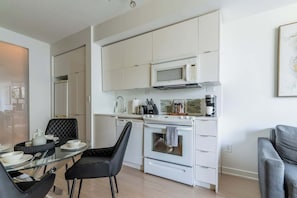 A modern kitchen with white cabinetry, a microwave, a stove, and a coffee maker. - 3BR/2BA City Views + Free Parking | Parking Available (Toronto)