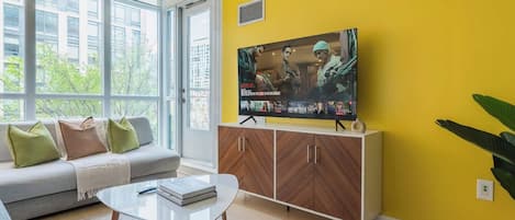 Una sala de estar con sofá, mesa de centro y televisor sobre un mueble.