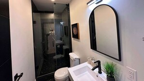 A modern bathroom with a glass-enclosed shower, a large mirror, and a white sink. - Cozy West End Gem! Bright 2BR w Huge Private Deck (Toronto)
