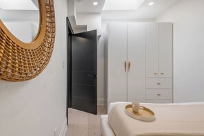 A modern bedroom with a bed, a wardrobe, and a wicker wall hanging.