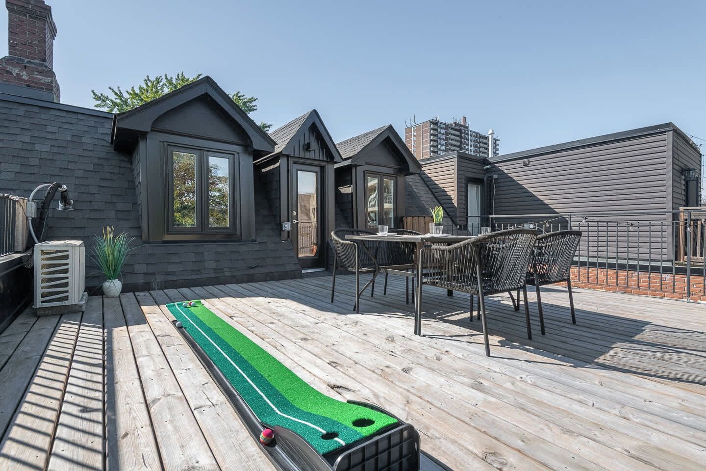 Une terrasse sur le toit aménagée avec un mini-parcours de golf, des sièges extérieurs et une vue sur le paysage urbain.