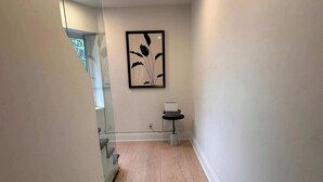 A hallway with a wooden floor, a framed artwork on the wall, and a small table with a basket. - Cozy West End Gem! Bright 2BR w Huge Private Deck (Toronto)