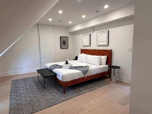 Une chambre à coucher avec un lit, un banc, une petite table et un tapis à motifs.