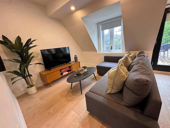 Un salon moderne avec un téléviseur à écran plat, un canapé, une table basse et une plante en pot.