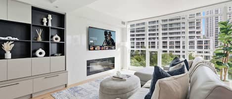 A modern living room with a large window, a flat-screen TV, and a sofa.