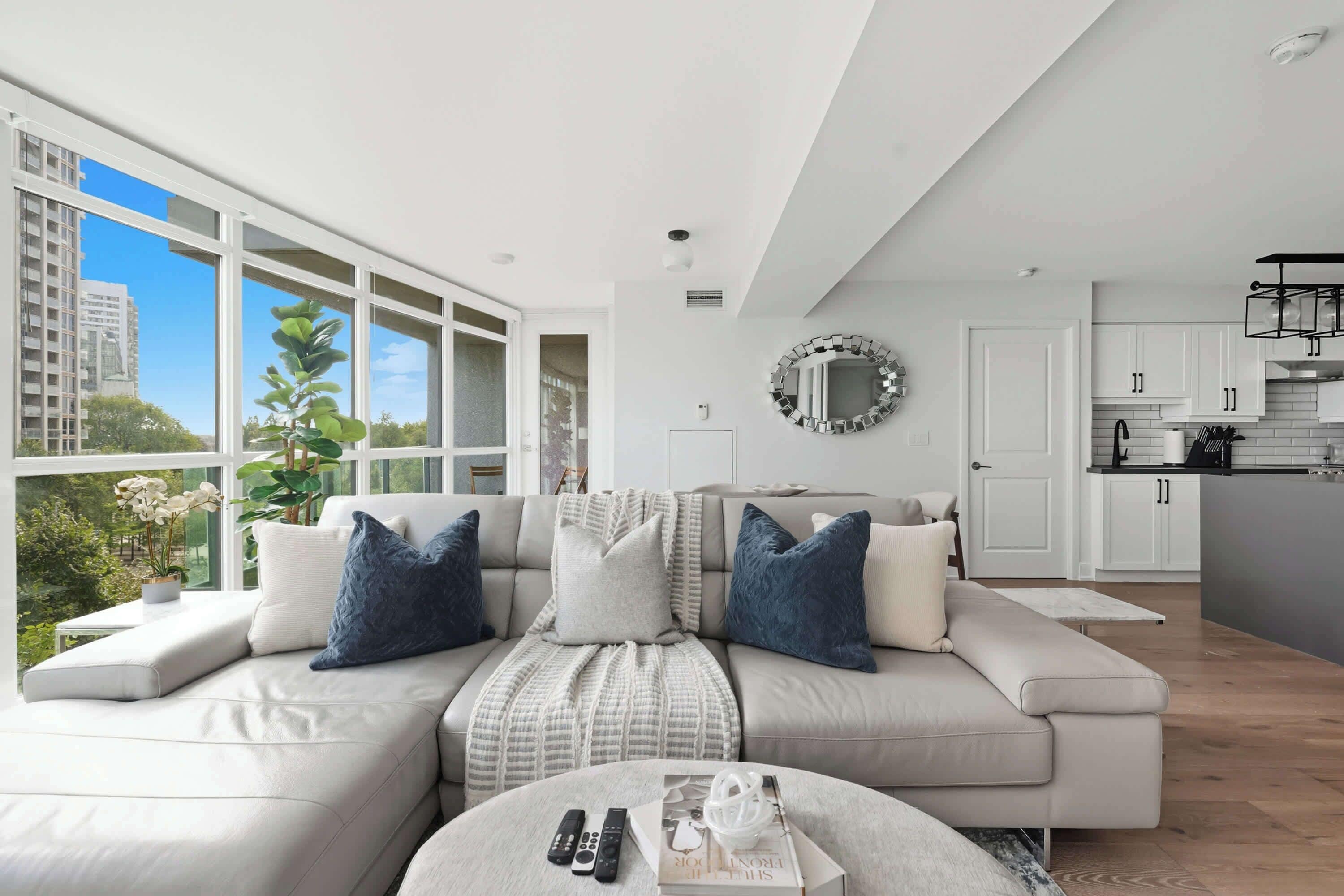 A modern living room with a sofa, a coffee table, and a view of the city.