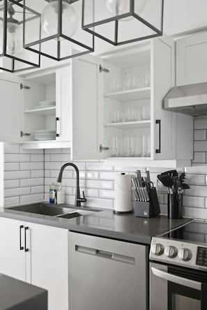 A modern kitchen with white cabinetry, a stainless steel sink, and a built-in oven. - Upscale 2BR Condo Downtown TO Gem w Parking | Parking Available (Toronto)