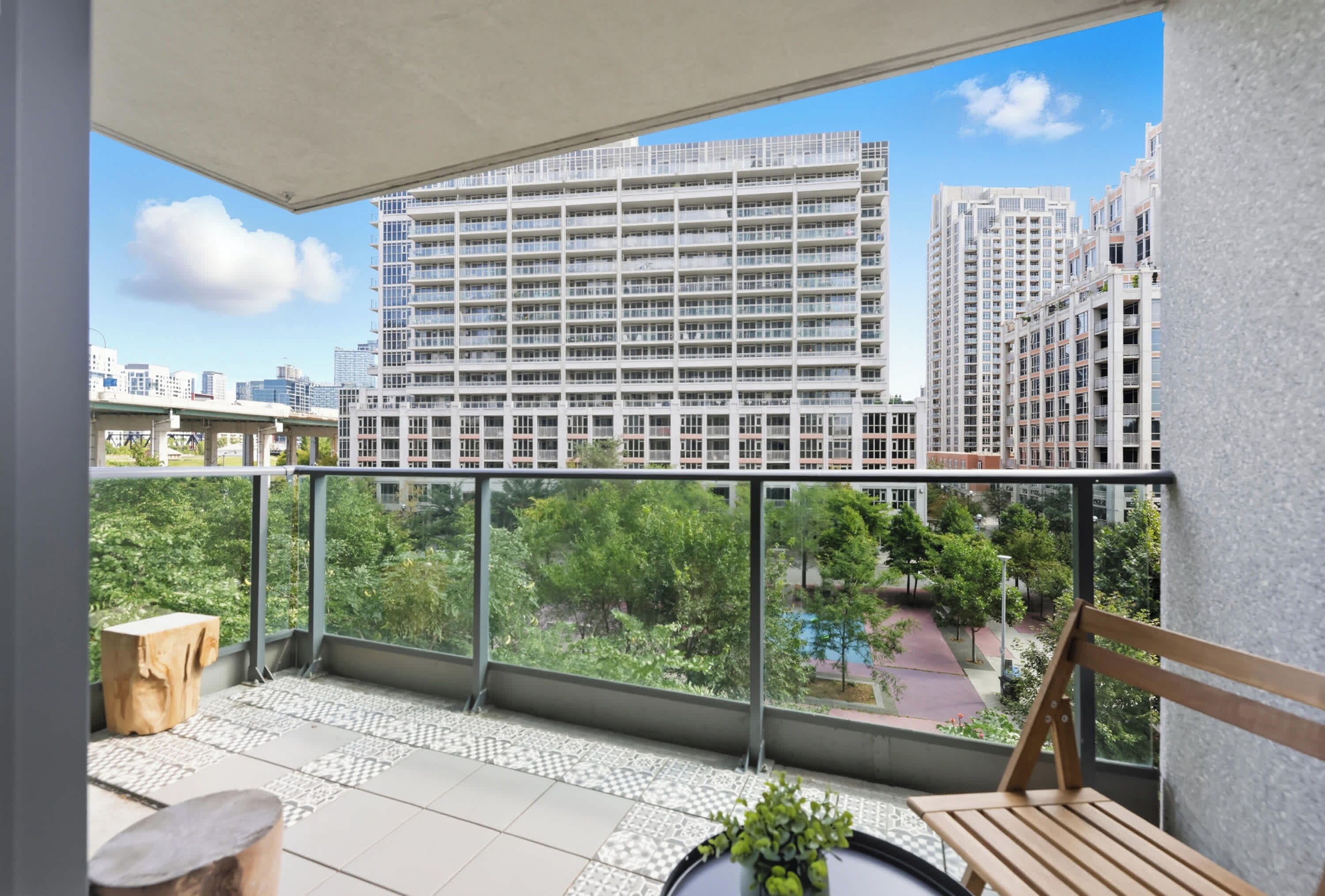 A balcony with a view of high-rise buildings, a tiled floor, and a wooden chair.
