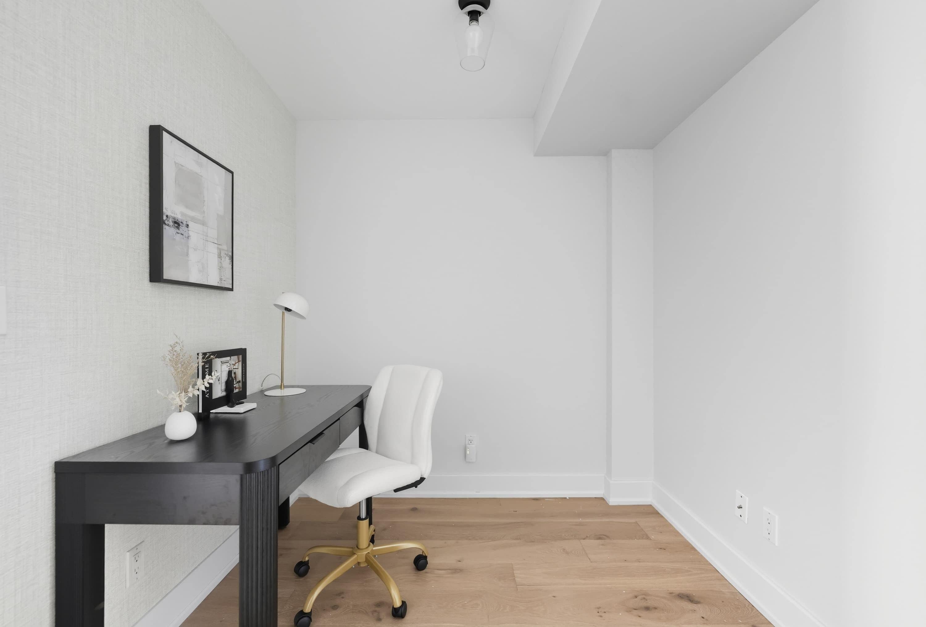 A minimalist office space with a desk, chair, and a framed picture on the wall.