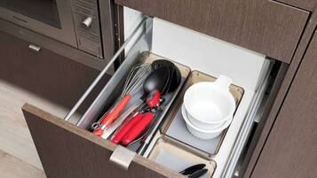 A kitchen drawer with utensils and dishes.