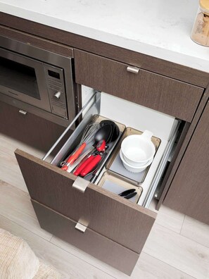 A kitchen drawer with utensils and dishes.