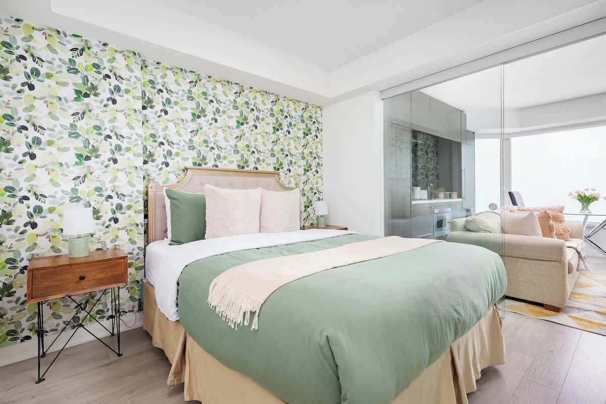 A modern bedroom with a large bed, a bedside table, a sofa, and a glass partition.