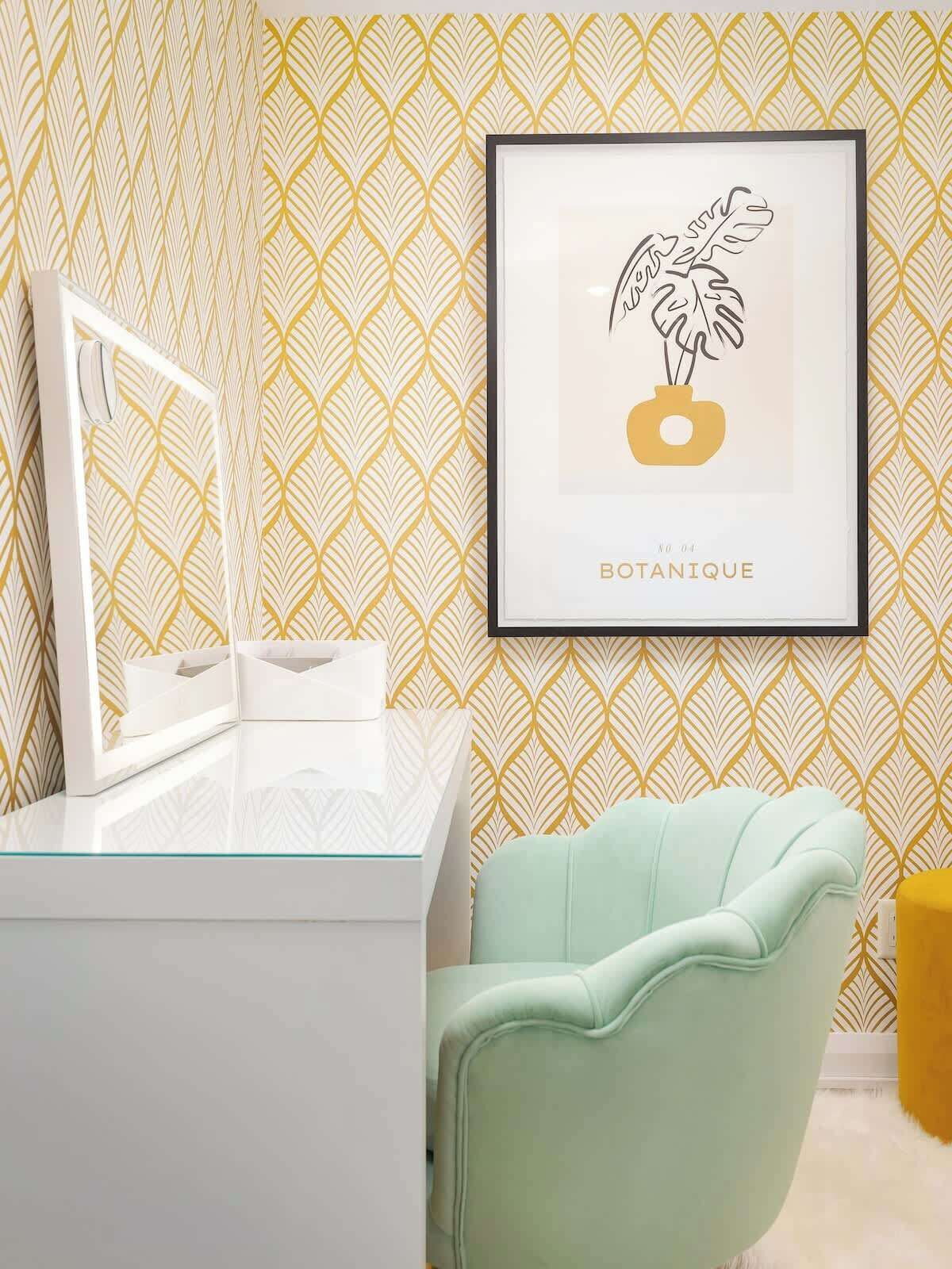A bathroom with a white vanity, a framed botanical print on the wall, and a mint green chair.