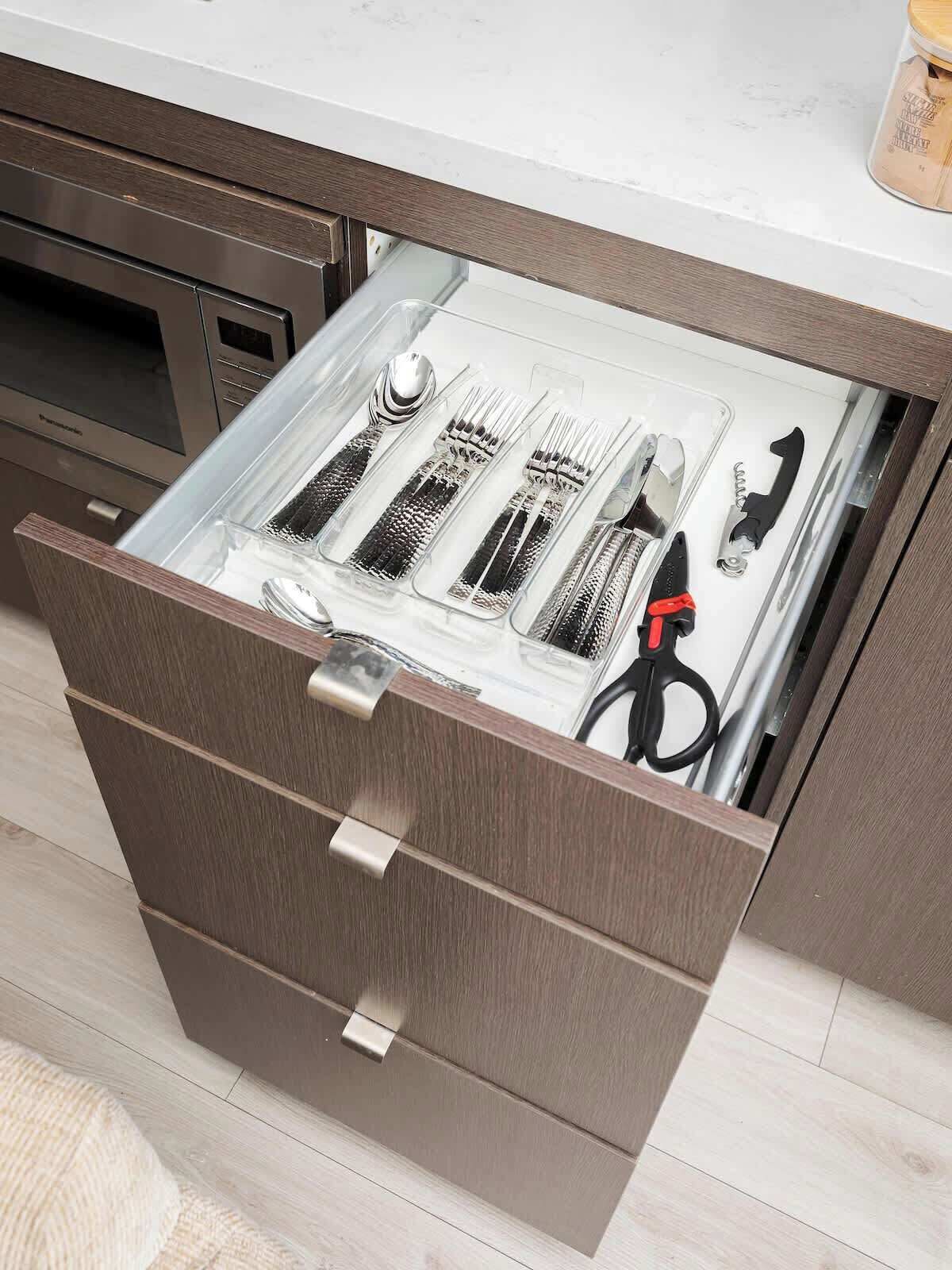 A kitchen drawer with utensils and a canister.