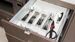 A kitchen drawer with utensils and a canister.