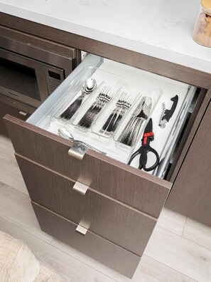 A kitchen drawer with utensils and a canister.